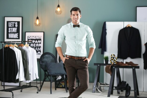 Key Fashion Upgrades That Improve Everyday Outfits 2 Man in a mint green shirt with a bow tie and brown pants posing confidently in a stylish modern wardrobe room.