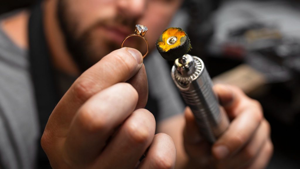 How Innovation Is Making Fine Jewelry More Accessible 3 Jeweler polishing a diamond ring using a rotary tool in a workshop.